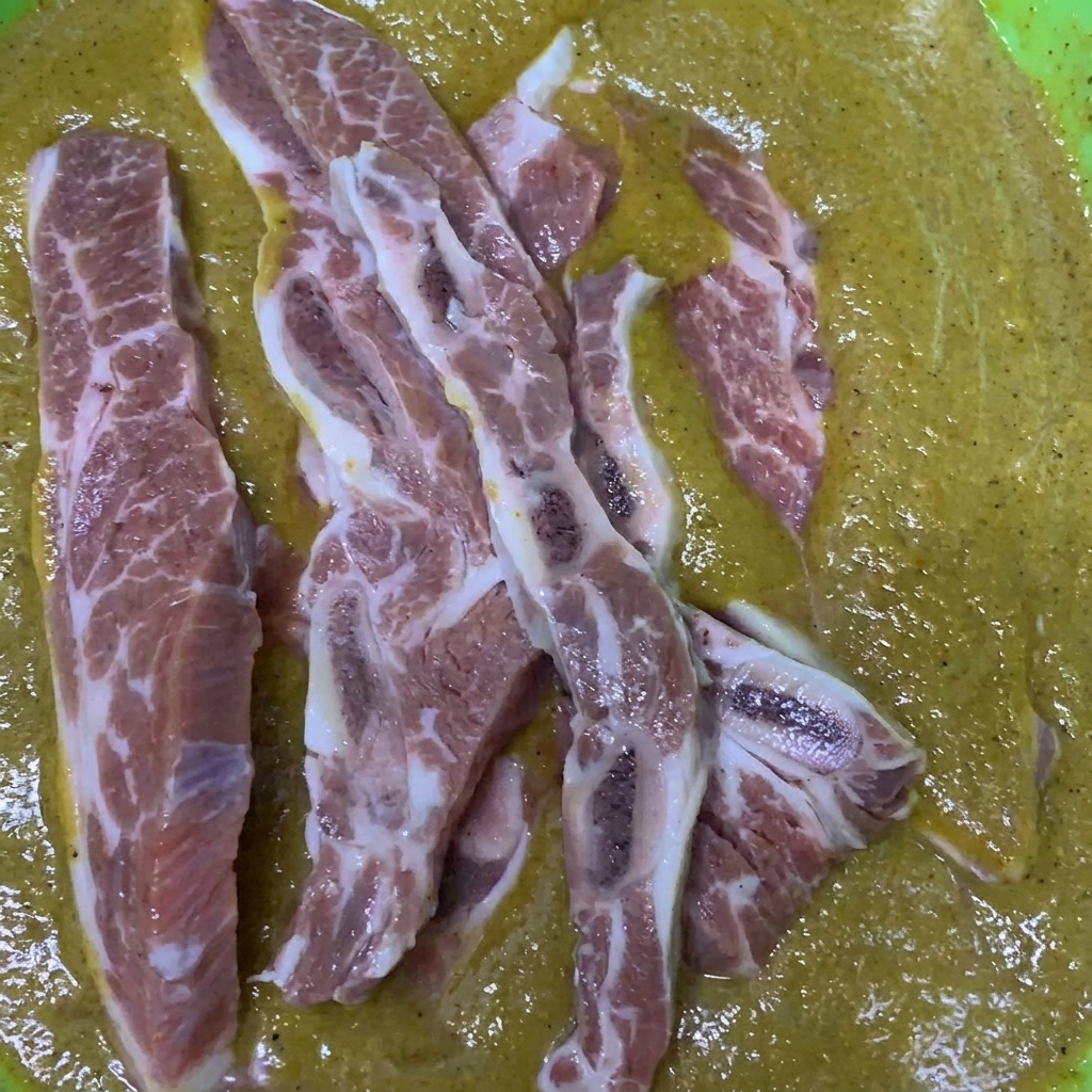 Beef short ribs being stirred and coated in a bowl filled with the prepared Korean-style marinade.