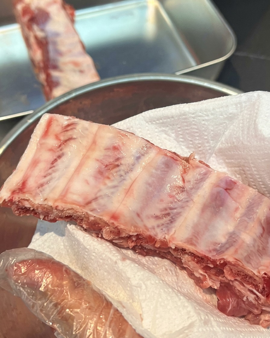 Raw pork ribs sitting on a white paper towel to absorb moisture.