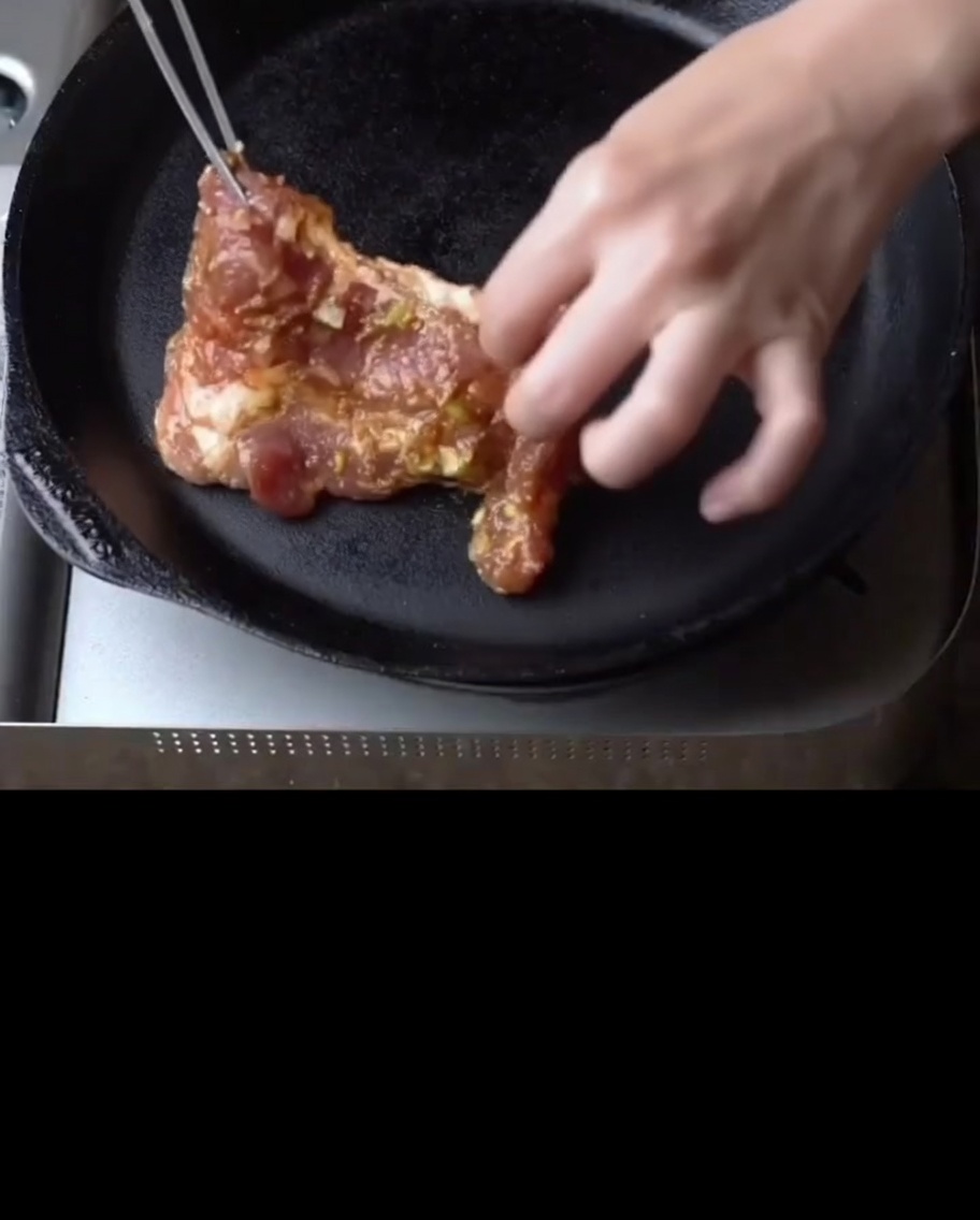 Marinated pork ribs sizzling in a preheated cast-iron skillet.