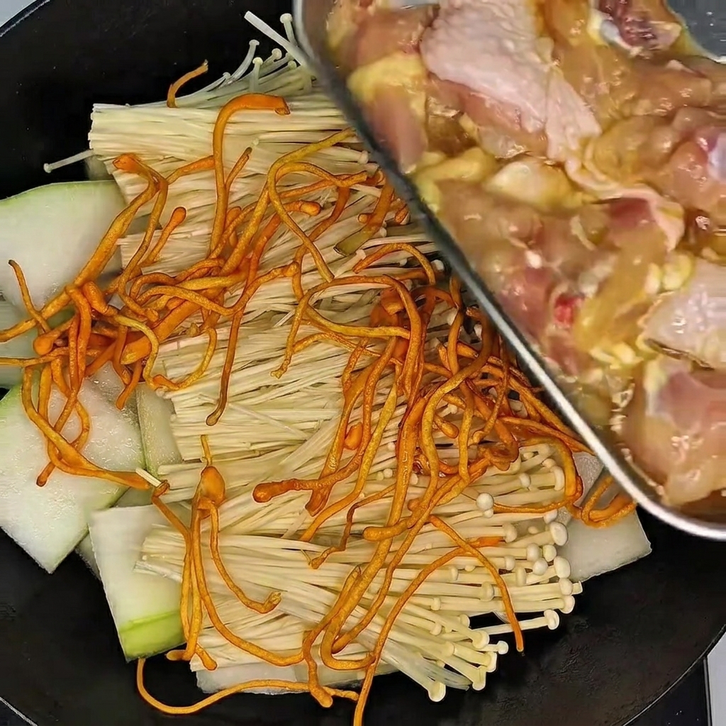 A gloved hand mixing and massaging the chicken drumsticks in a bowl of marinade.