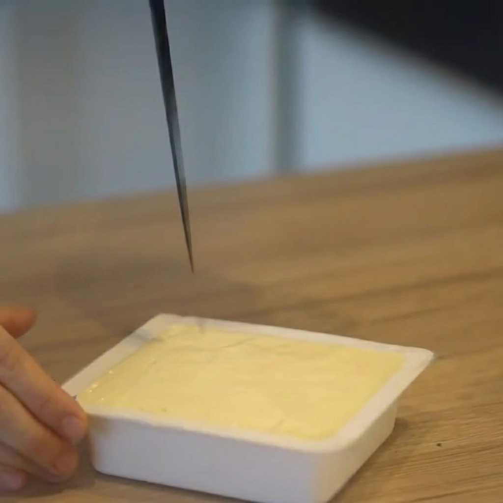 Tofu being sliced into cubes while still in its plastic package.