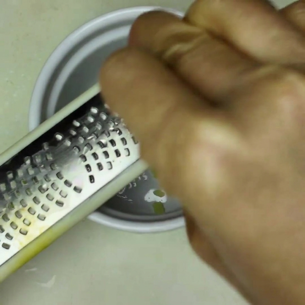 A small white bowl containing a red, seasoned sauce mixture being stirred with a spoon.