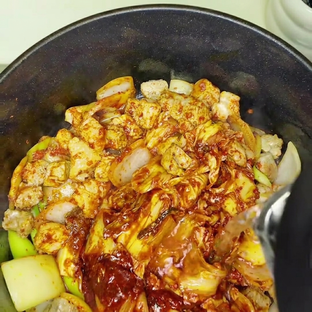 Water being added to the pot of kimchi and pork, starting the simmering process.