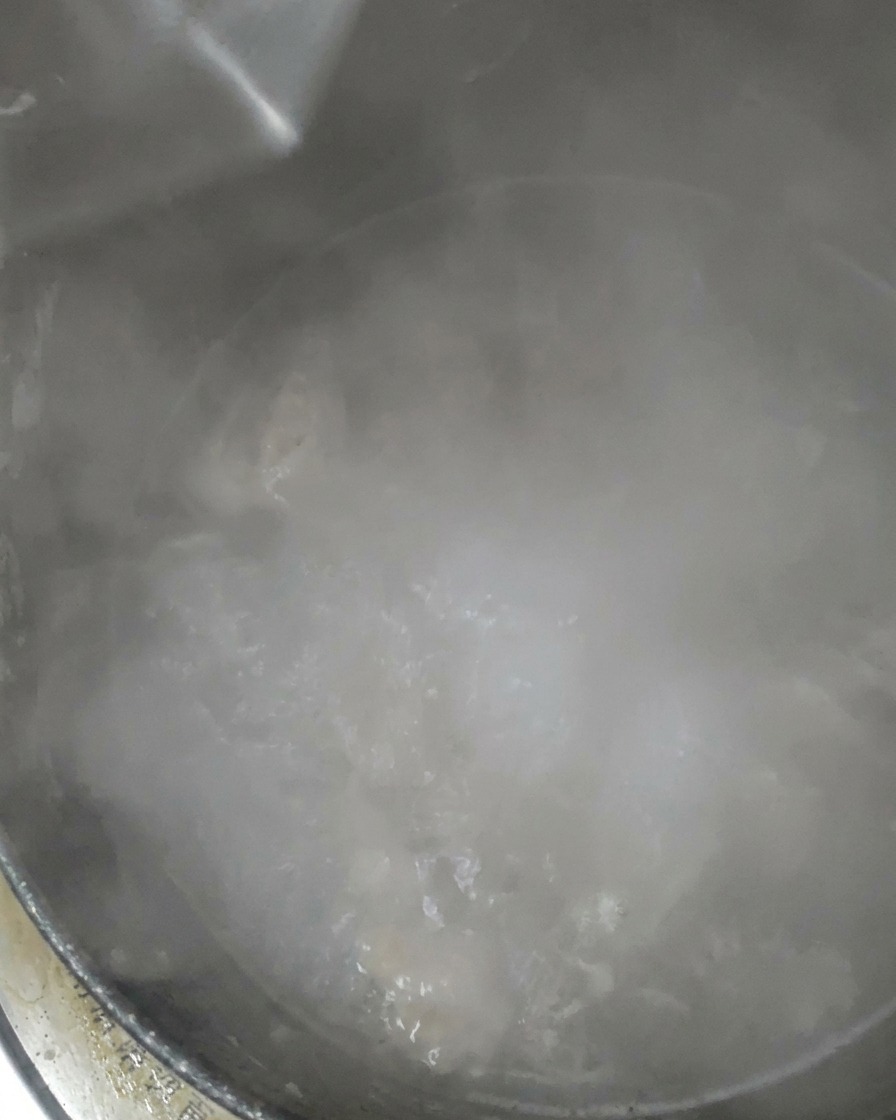 Clear water being poured into a pot that has been simmering.