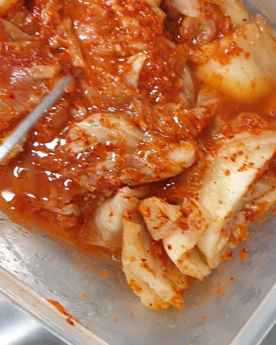 Tongs placing pieces of fermented kimchi into a bubbling pot.