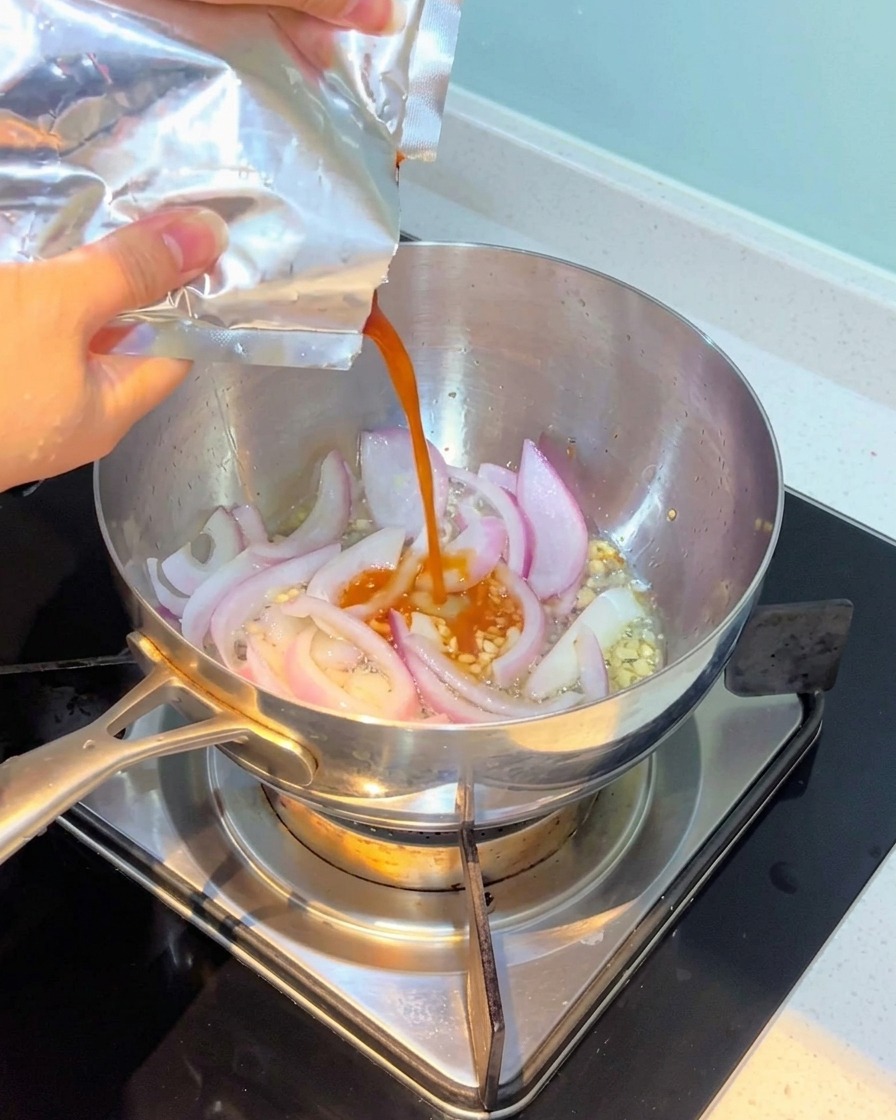 Kimchi being poured into the pot and mixed with onions and garlic.