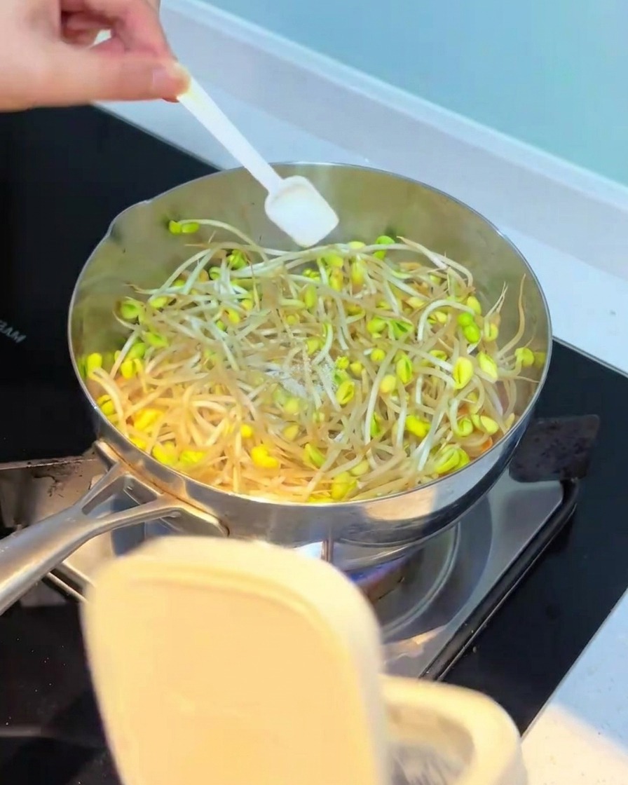 Seasonings being added to the pot with the bean sprouts.