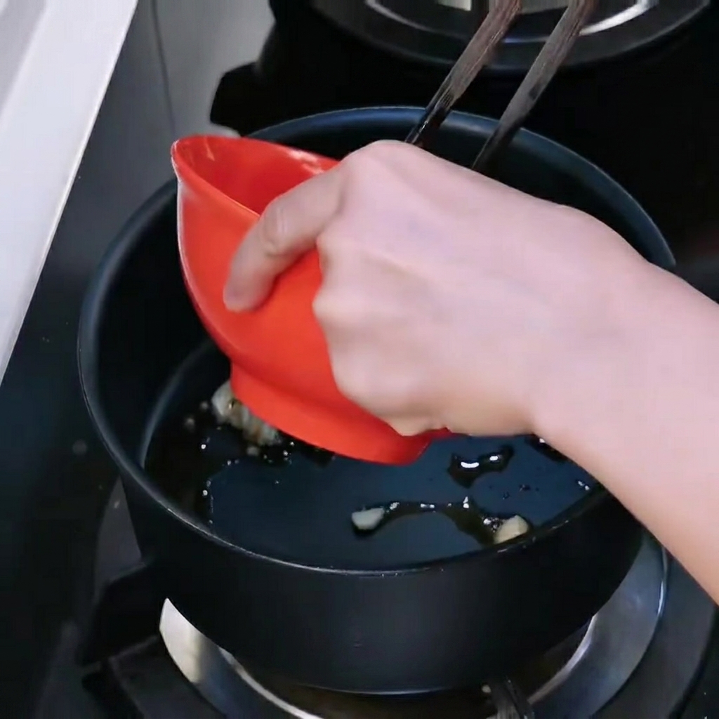 Ground beef being added to the pot to stir-fry with the garlic.