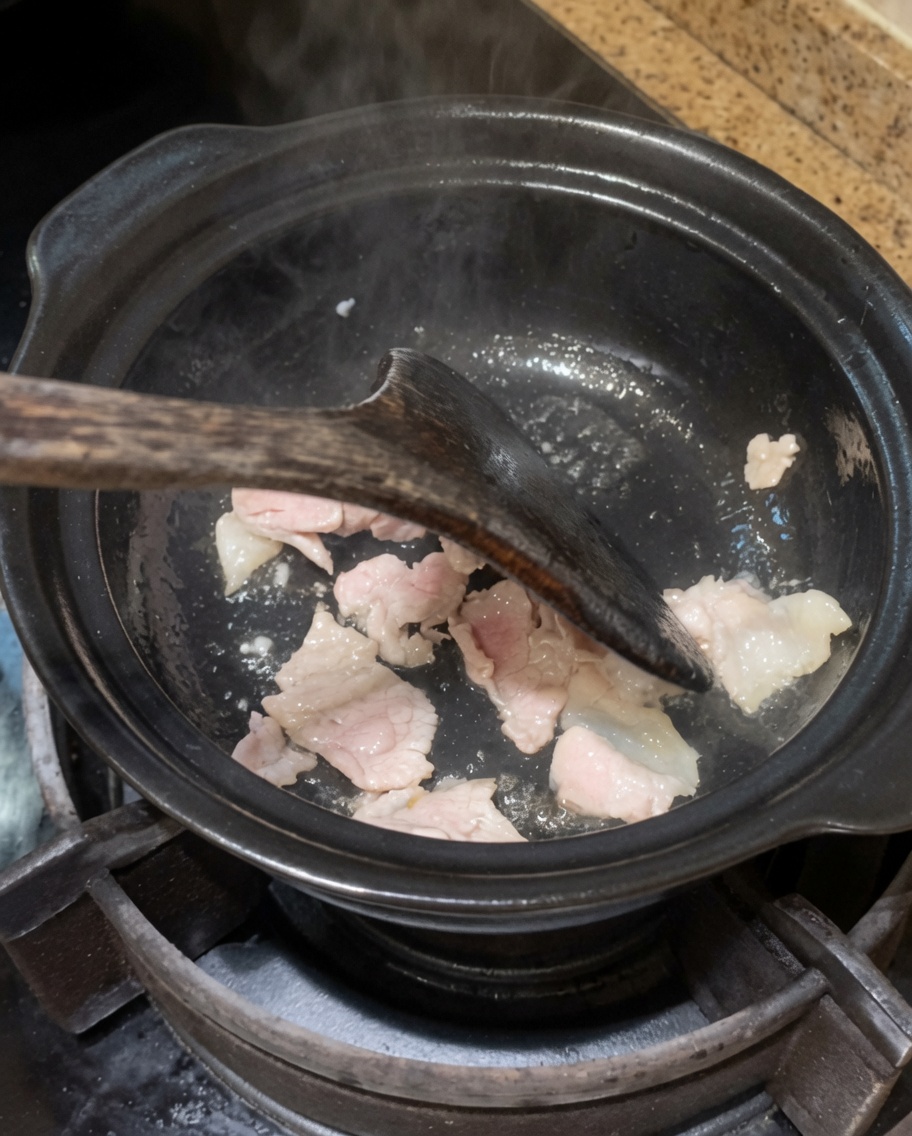 Onion and garlic being stir-fried in the pot with the pork.