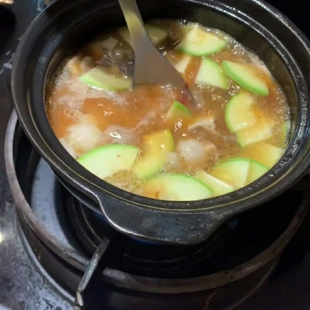 Sliced zucchini and cubed potatoes being added to the stew.