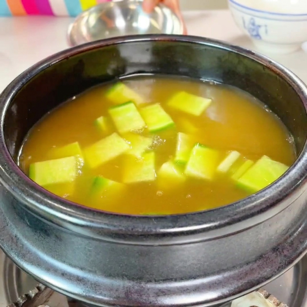 Diced green zucchini and sliced mushrooms being added to the pot.