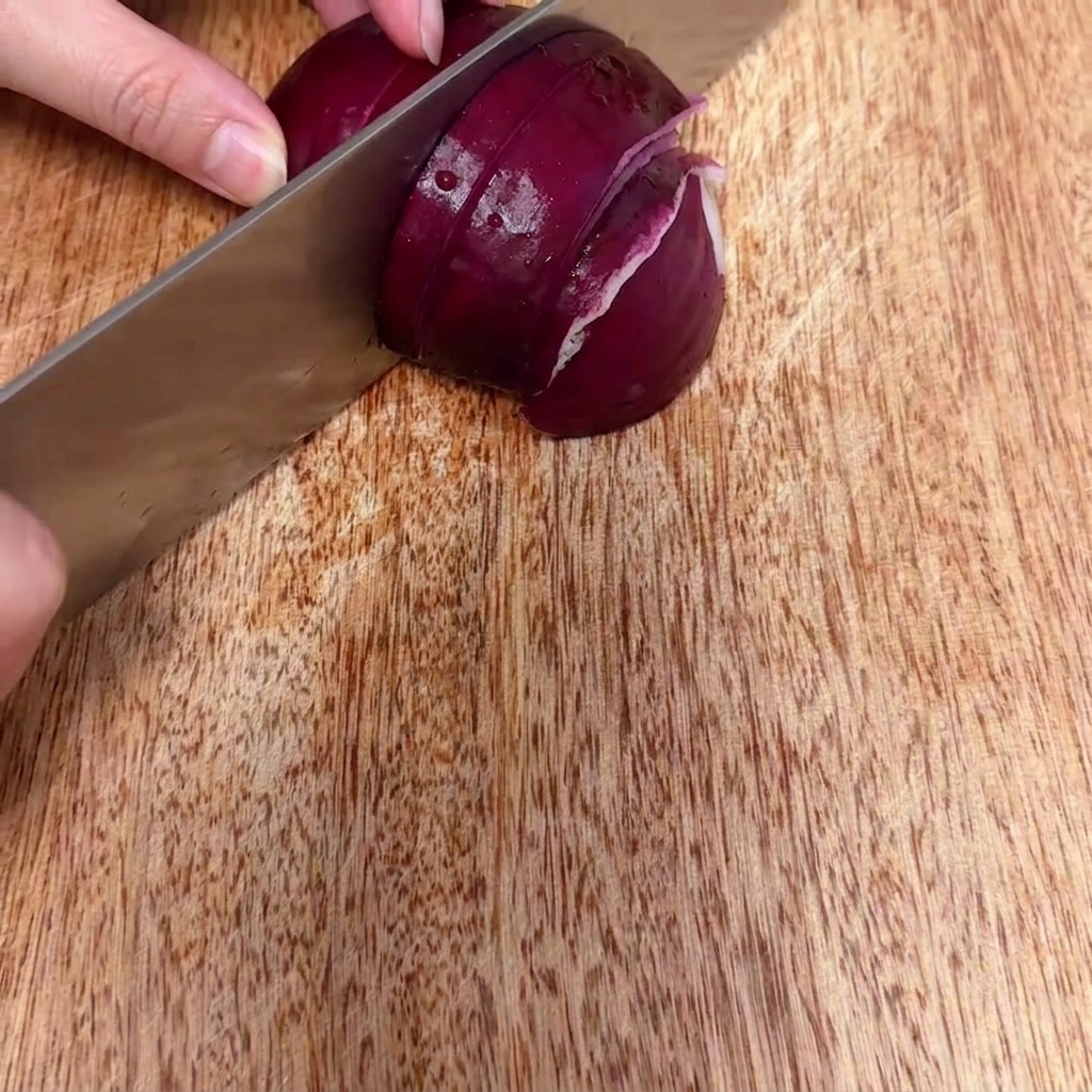 Red onion being chopped into fine, small pieces on a wooden surface.