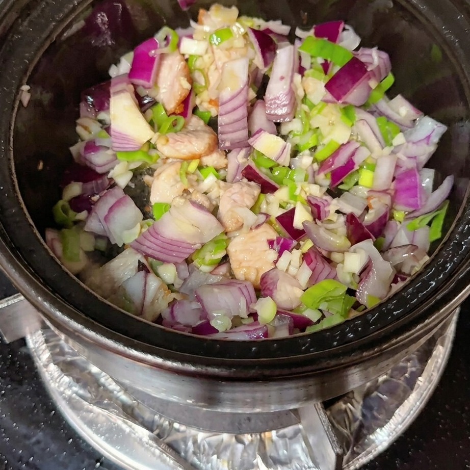 Korean chili paste and red chili powder being incorporated into the pork and aromatic mixture.