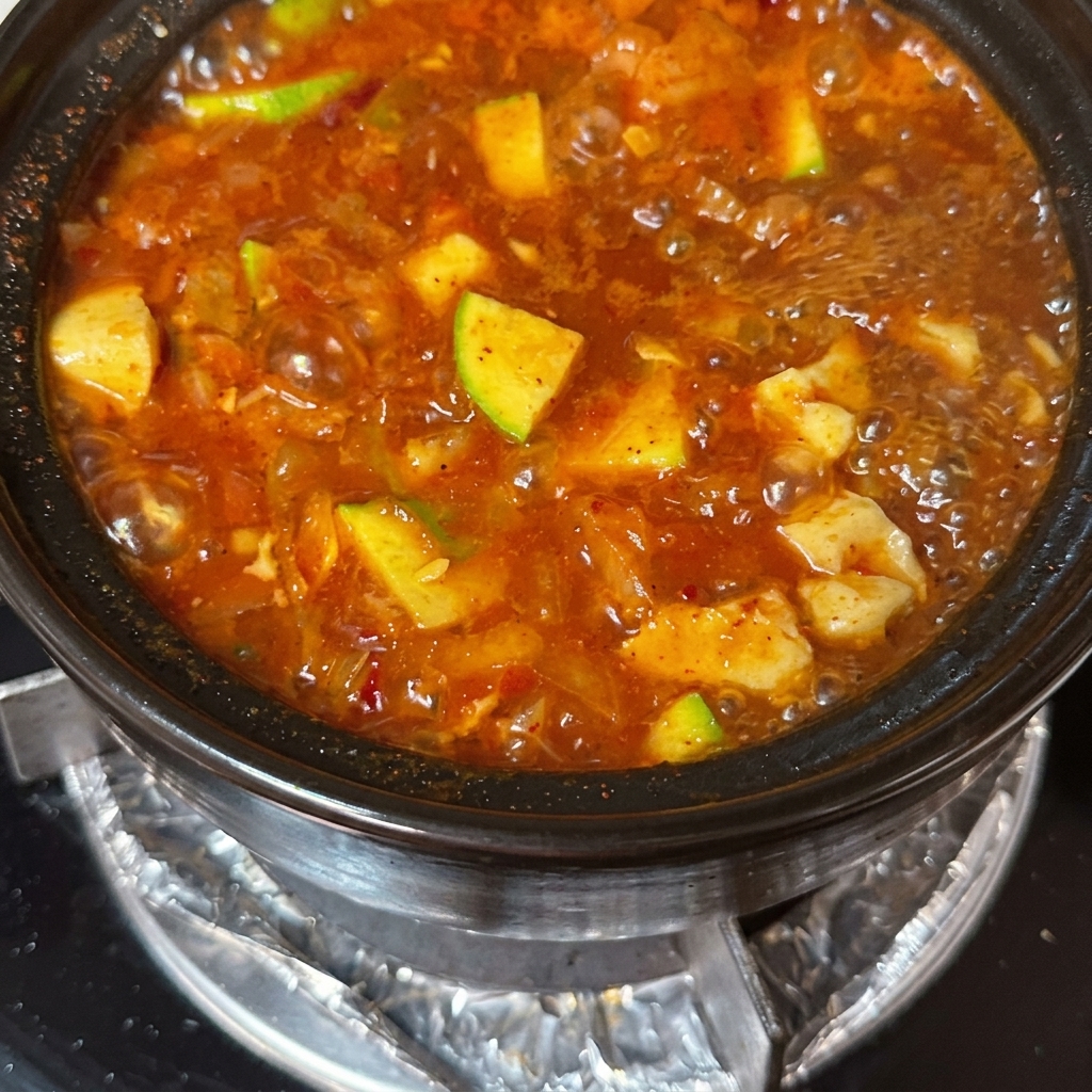 Thin slices of beef and raw eggs being added to the simmering soup.