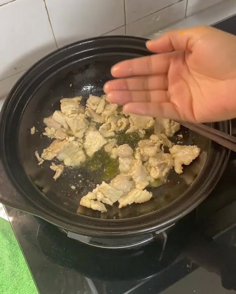 Ginger, garlic, scallions, and dried chili being stirred into the cooked pork belly.