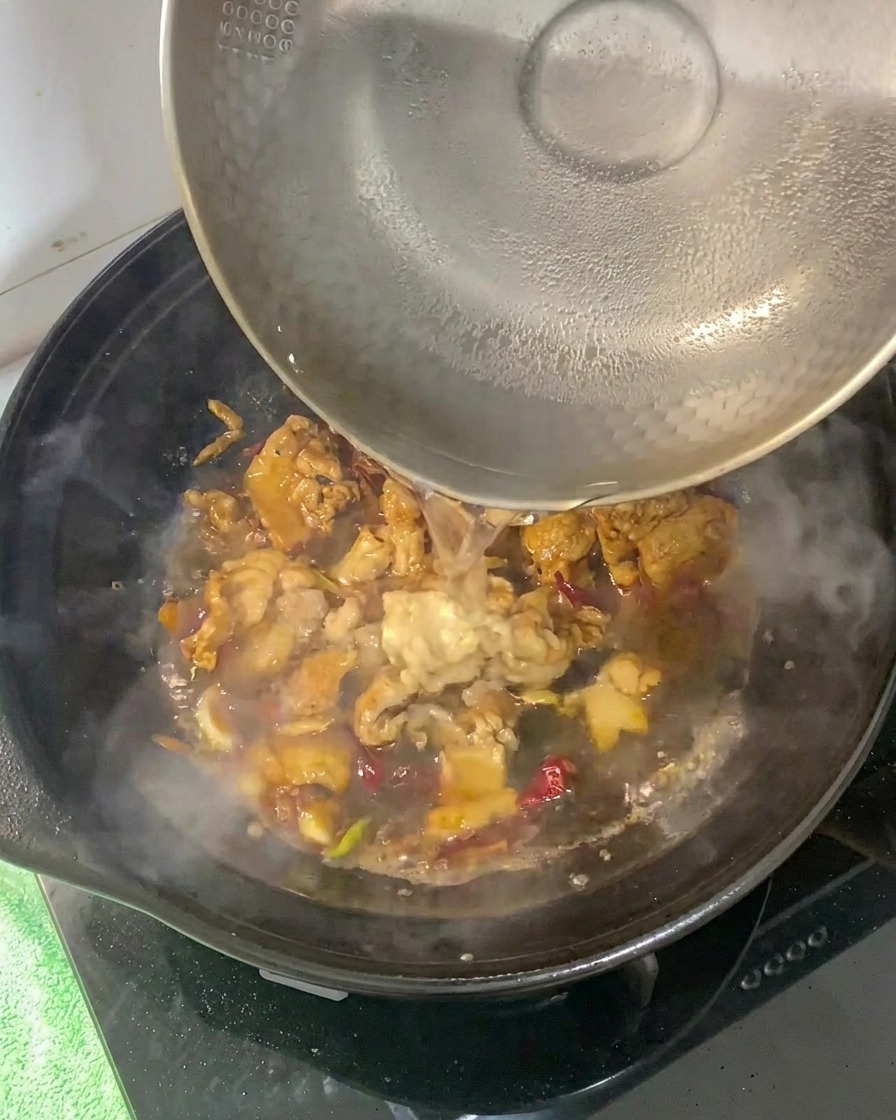 Hot water being poured into the clay pot with the seasoned pork base.