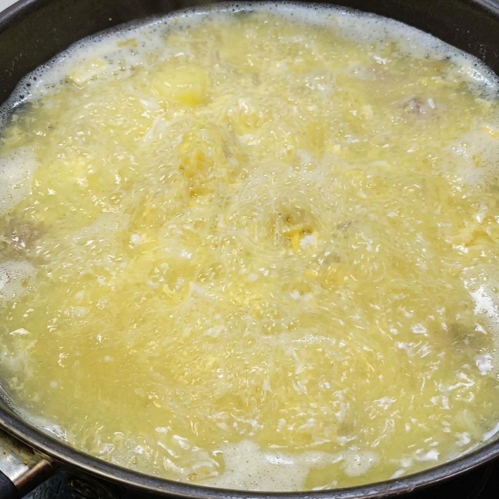 Salt and white pepper being seasoned into the simmering tofu and salted egg soup.