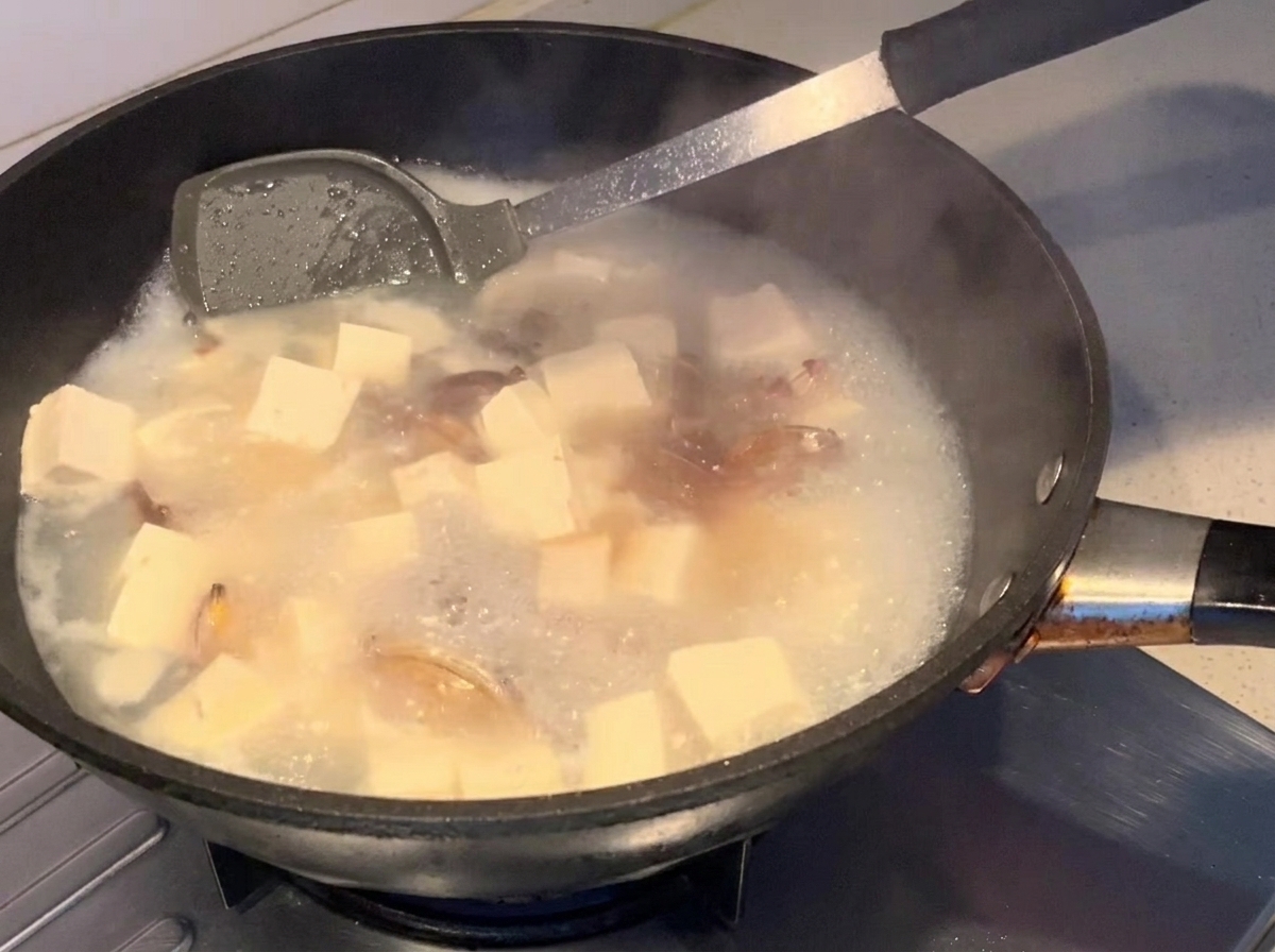 Soy sauce being swirled into the simmering soup.