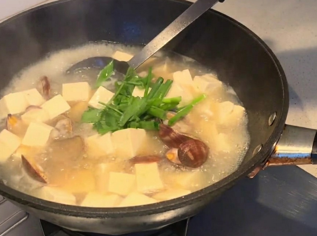 Fresh herbs being sprinkled over the finished soup.