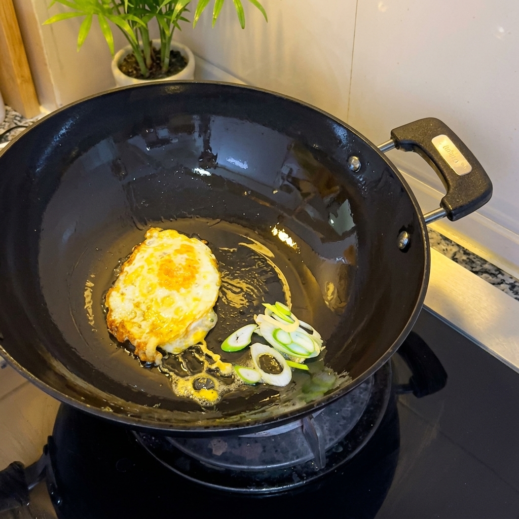 Fried egg and chopped green onions sizzling in the wok.