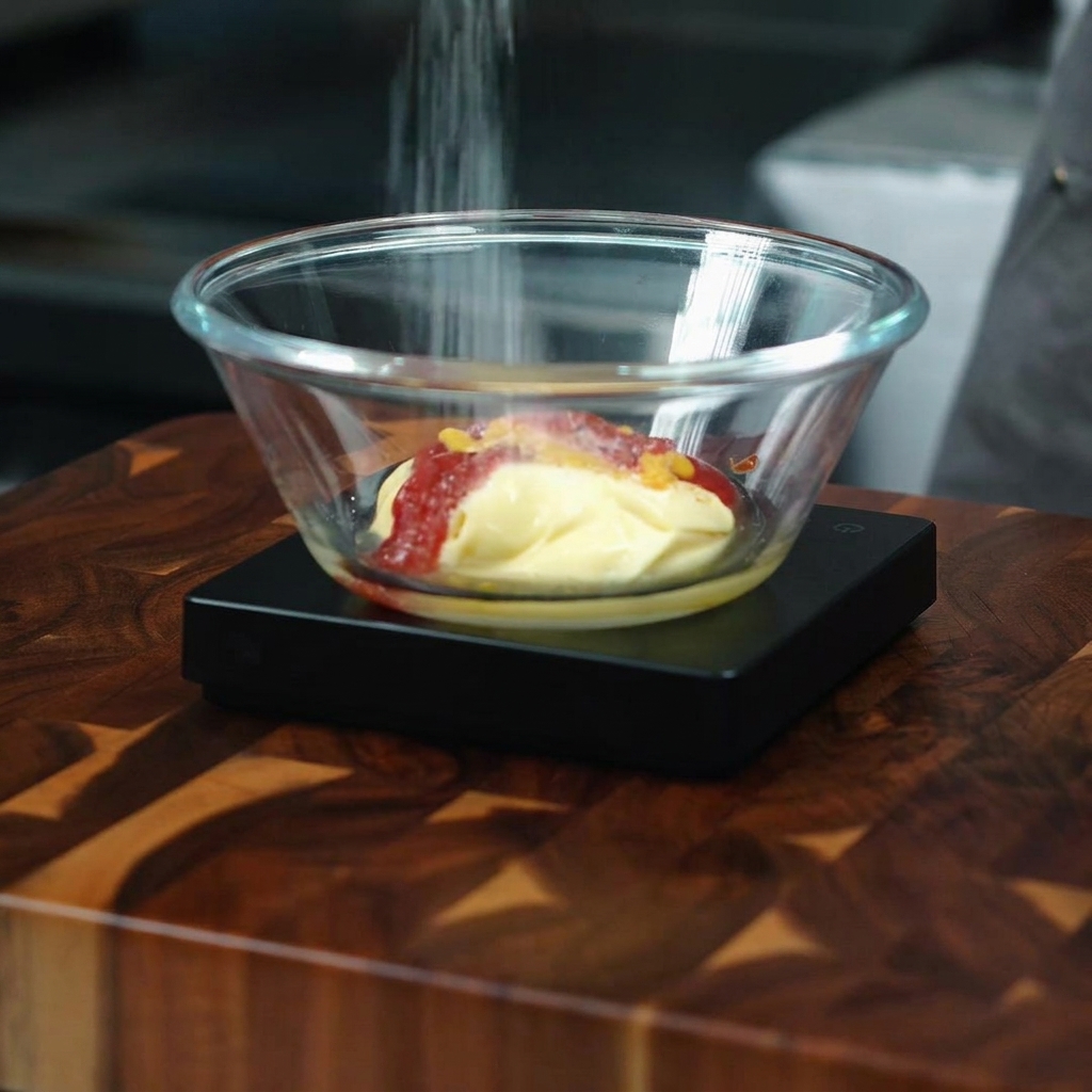 Sugar being added with a spoon to the mixture in the glass bowl.