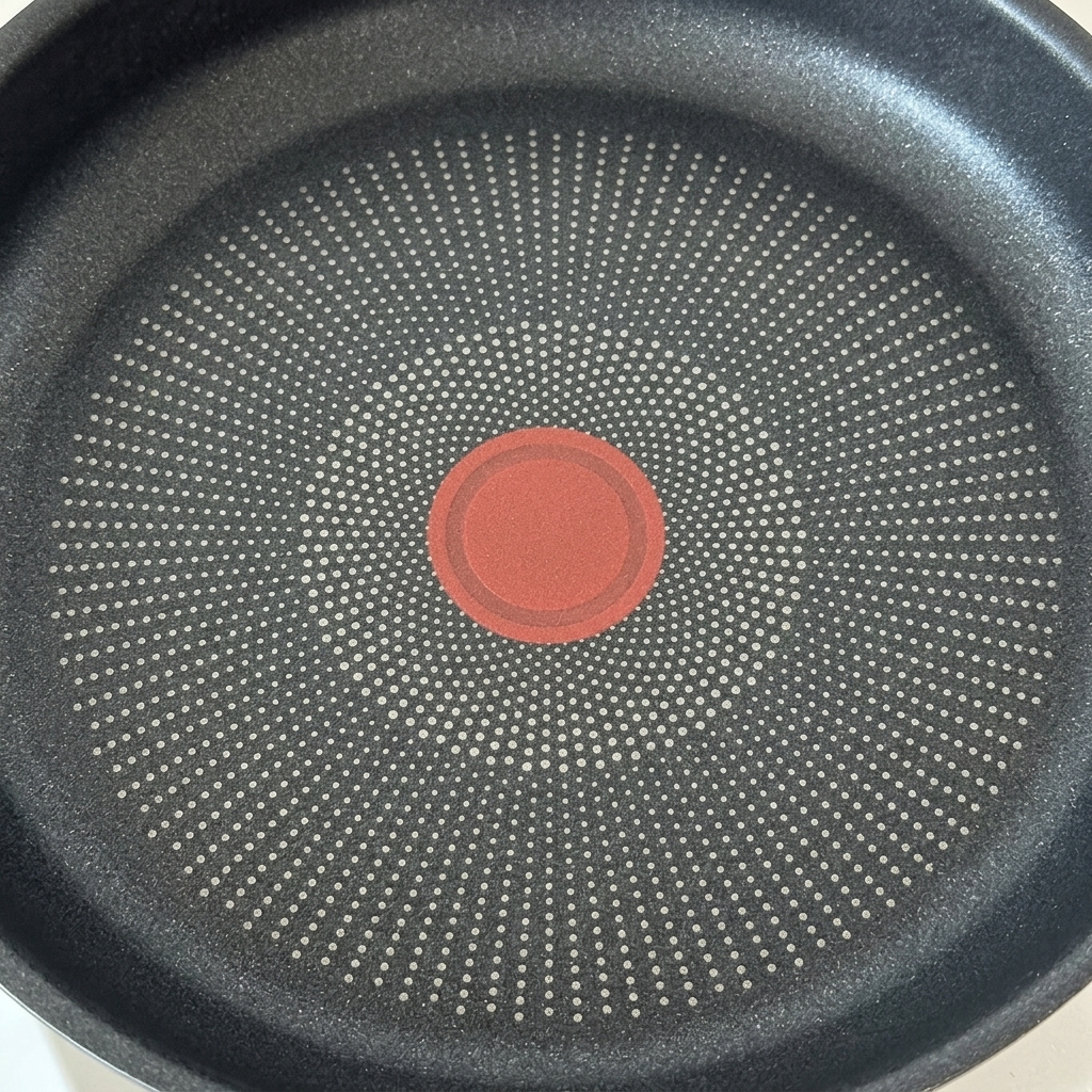 Two hamburger patties cooking in a hot, lightly oiled frying pan.