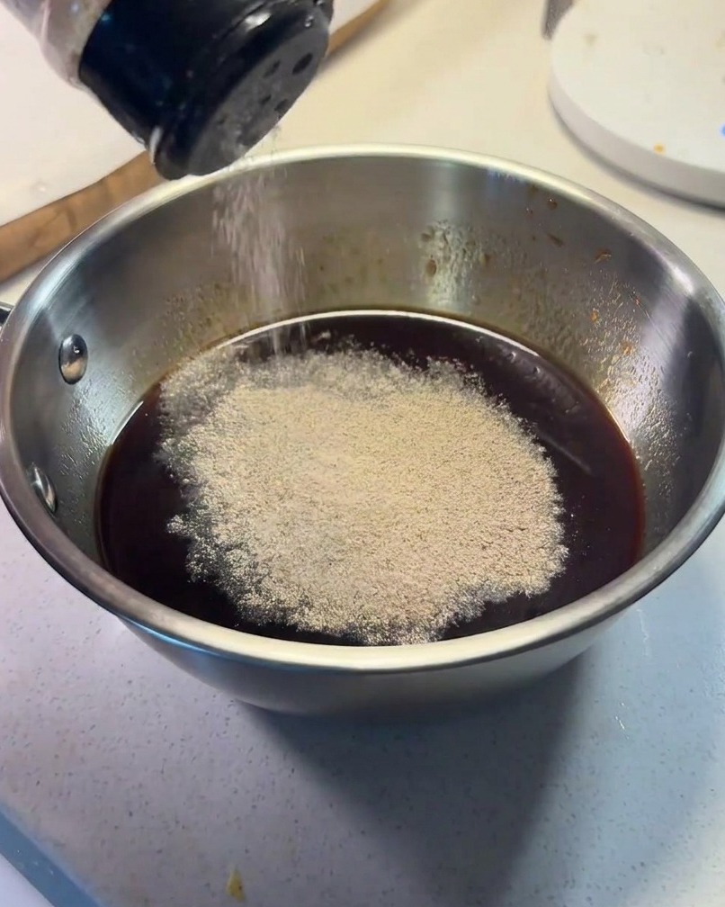 Sauce ingredients being combined in a small metal bowl with black pepper being sprinkled on top.