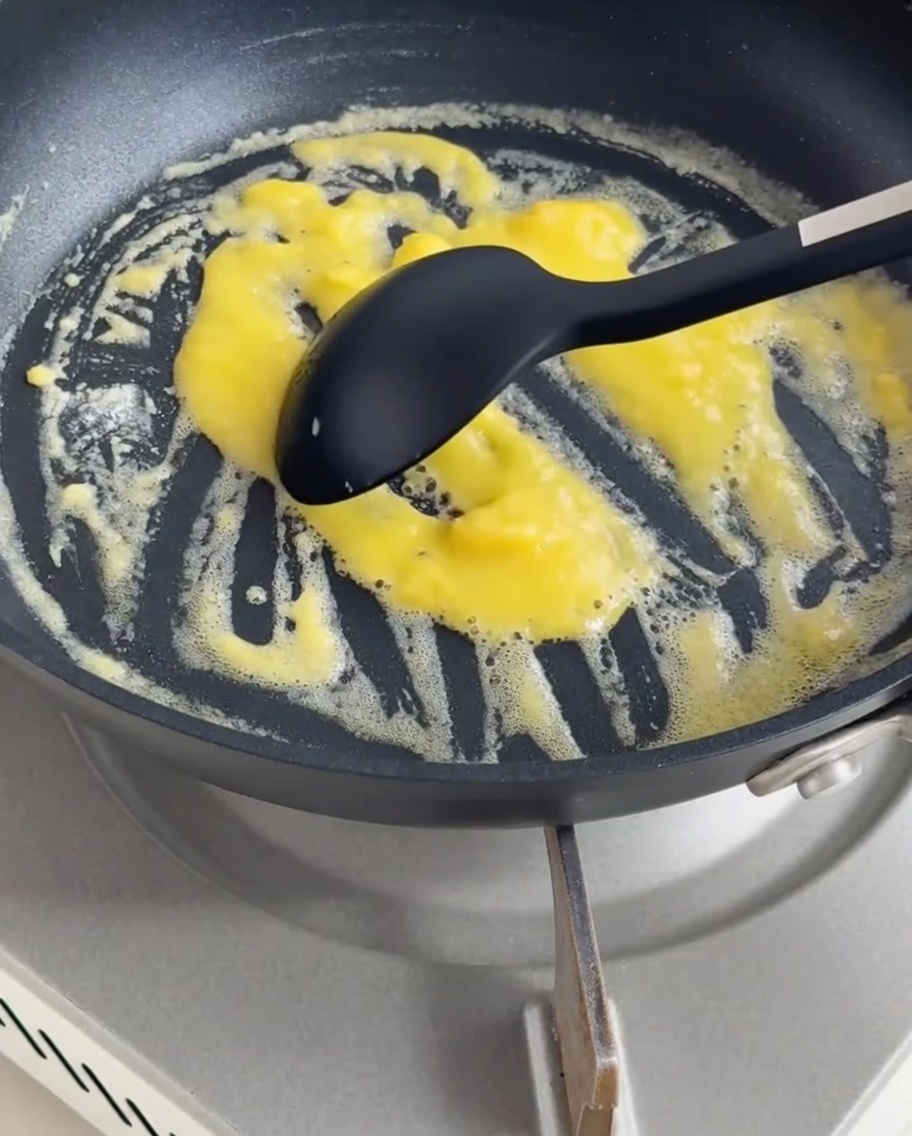 Cream and milk being poured into a pan containing roux, whisked into a smooth, thick white sauce.