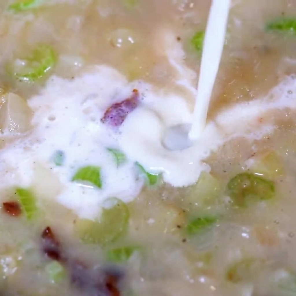 Adding chopped clam meat into the bubbling creamy soup.