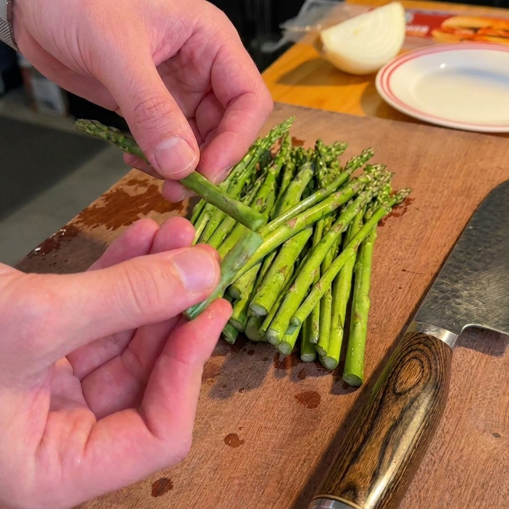 Asparagus spears arranged on a wooden board with the woody ends removed and stems chopped into smaller segments.