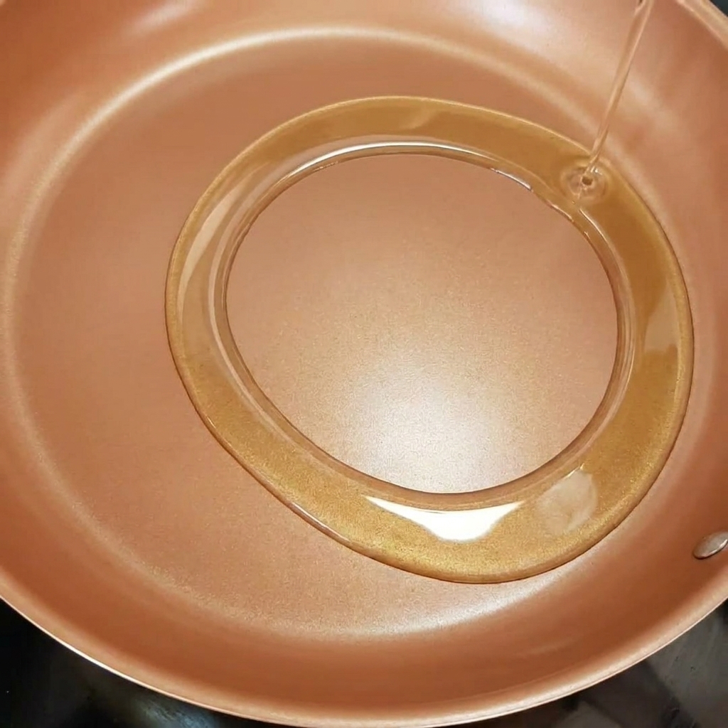 Onion strips frying in a pan with shimmering hot olive oil.
