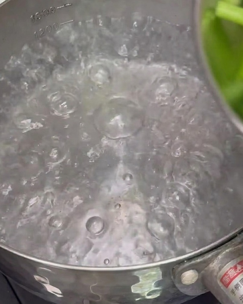 Asparagus pieces boiling in a pot of water to blanch them.