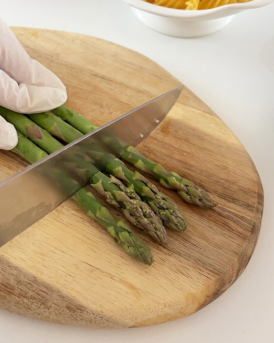 Fresh green asparagus stalks being neatly sliced into equal sections on a wooden board.