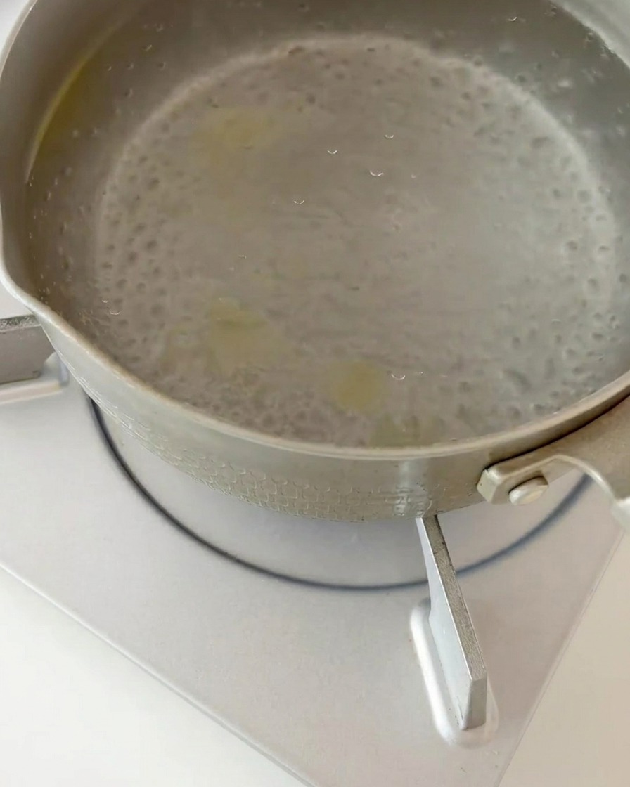 Cooked fusilli pasta being strained from boiling water in a kitchen colander.
