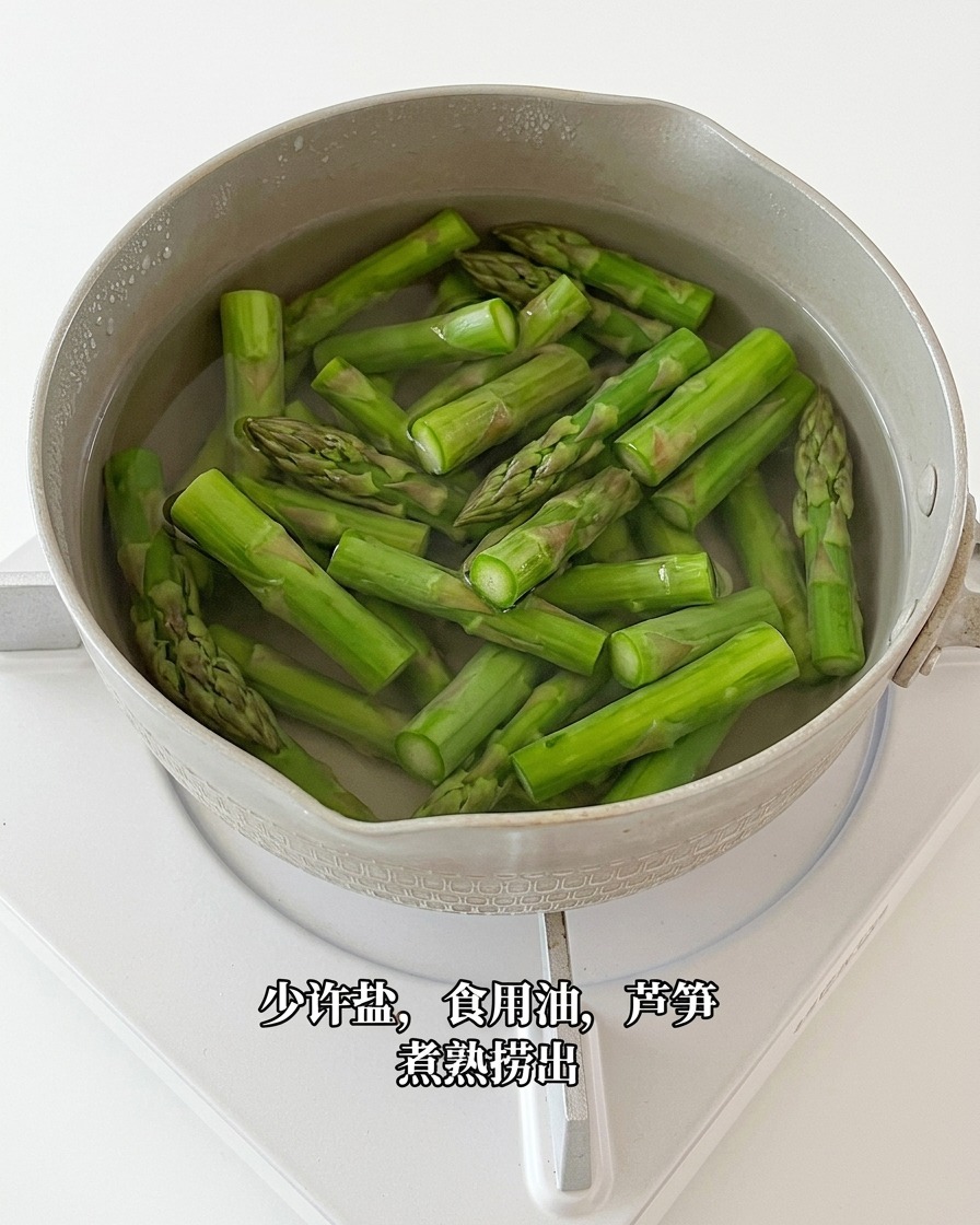Blanched asparagus pieces being lifted from boiling water with a slotted spoon.