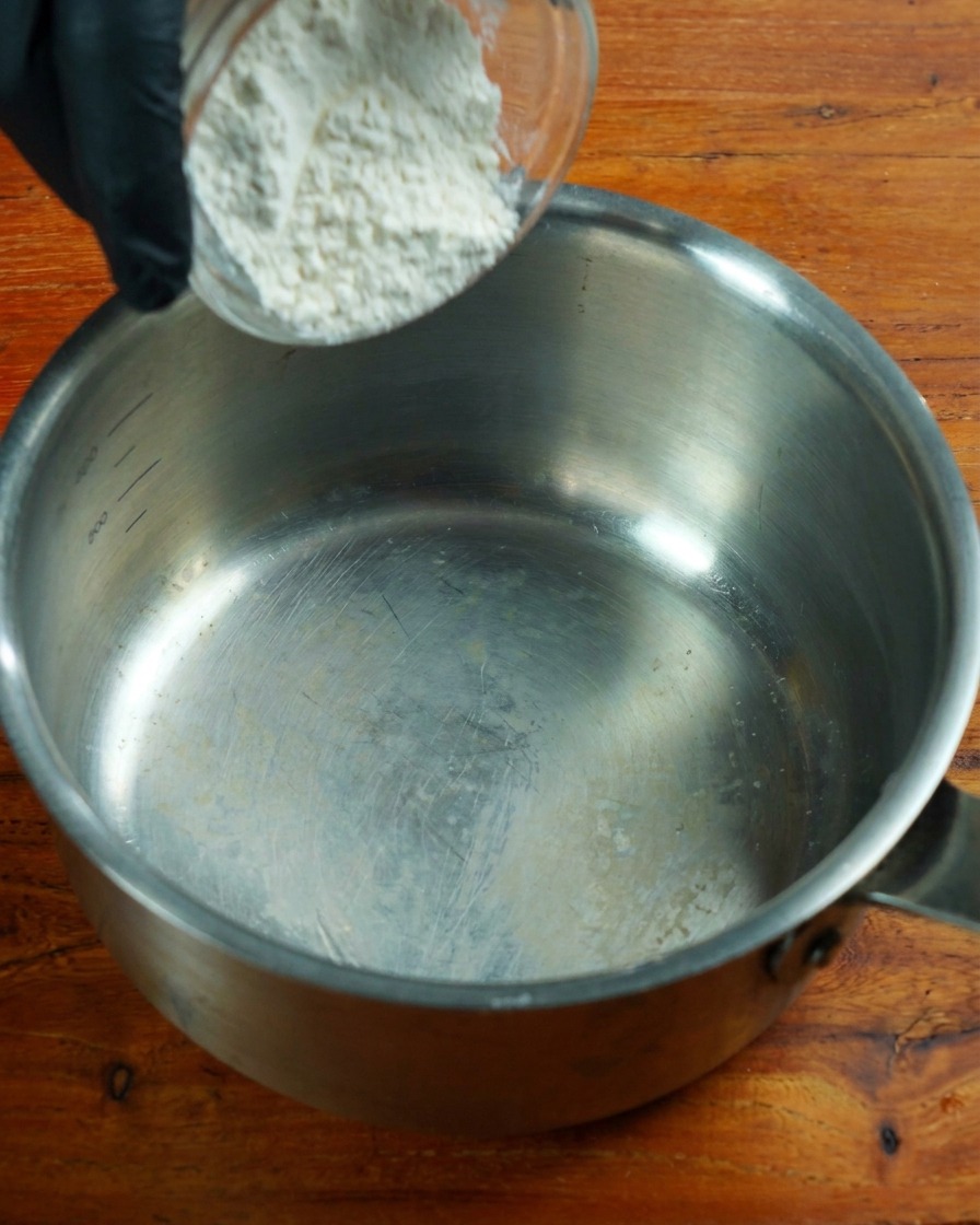 Low-protein flour being stirred in a stainless steel pot over low heat.