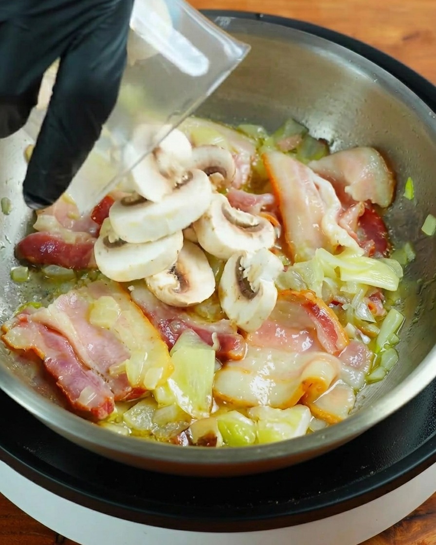 Slices of fresh white button mushrooms being poured from a container into a pan with frying bacon.