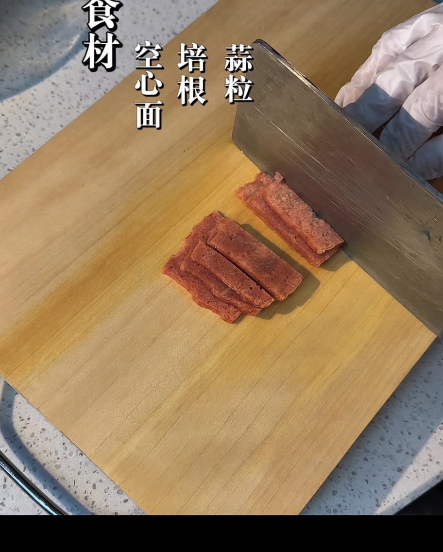 Bacon strips being cut into smaller pieces on a wooden board.