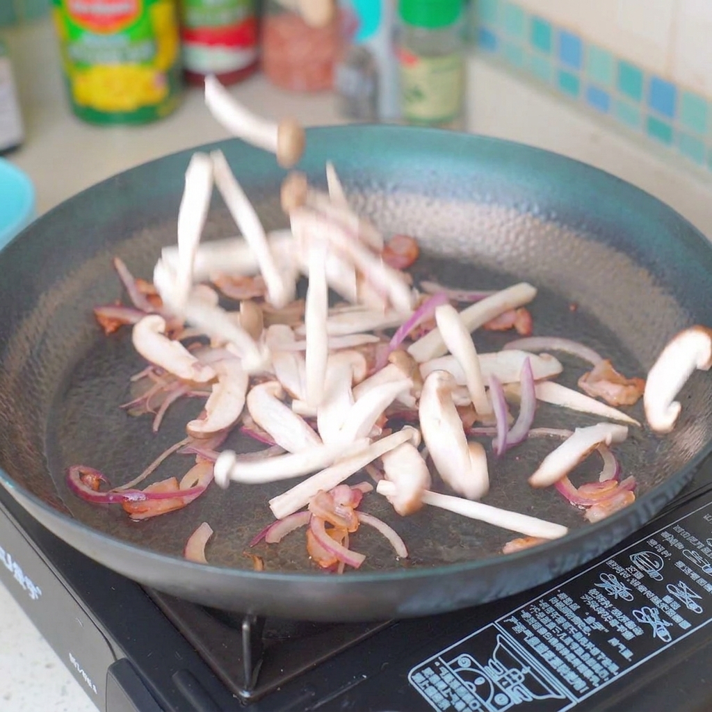 Sliced mushrooms and onions being stir-fried in a pan with bacon.