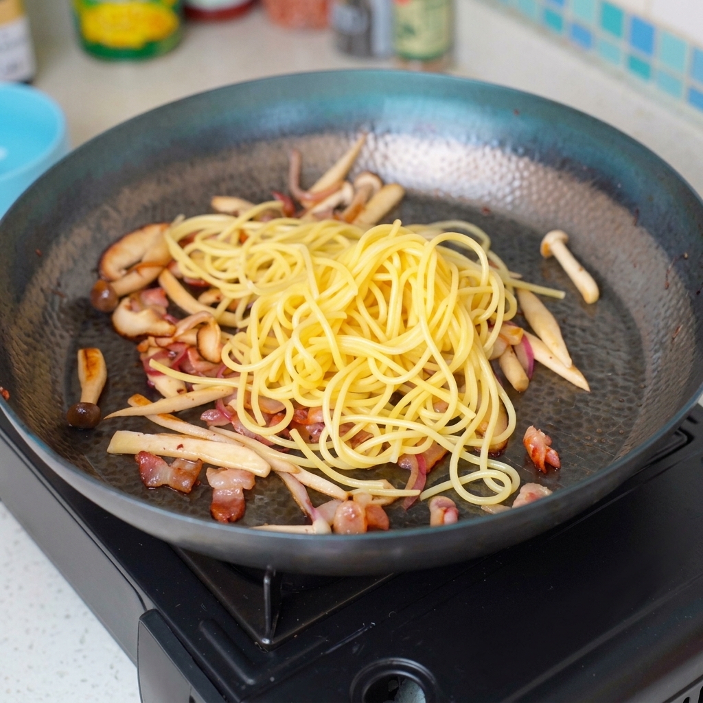 Angel hair pasta being stirred into the sautéed ingredients in the pan.