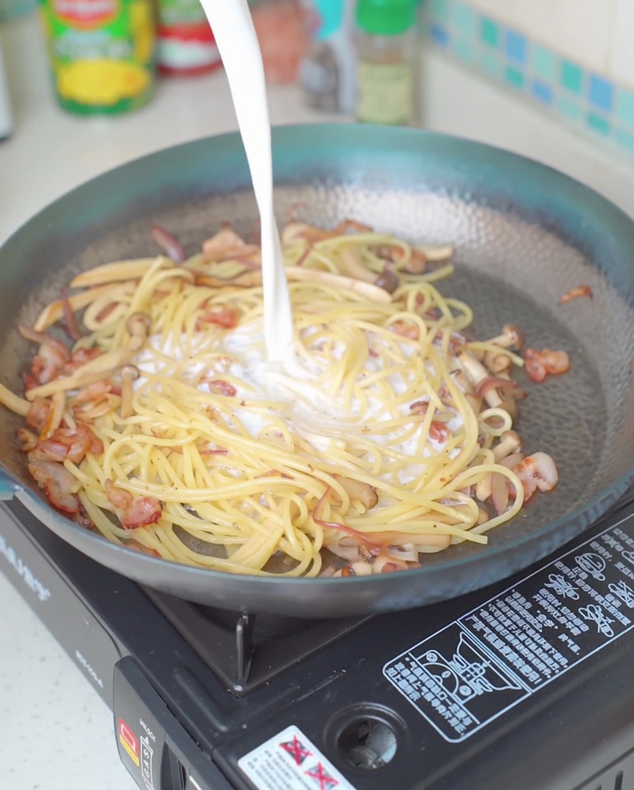 Milk being poured into the pan over the pasta mixture.