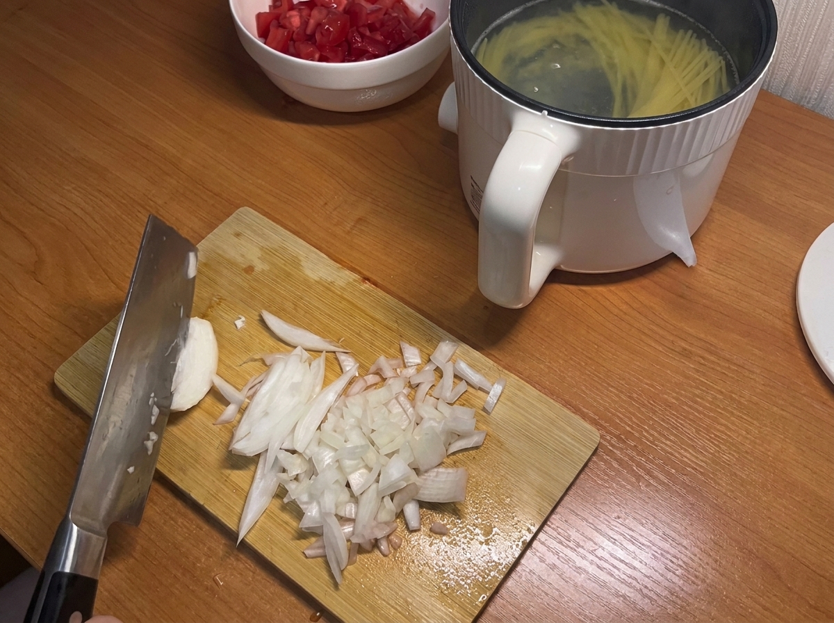 A white onion being diced into small pieces on a wooden cutting board.