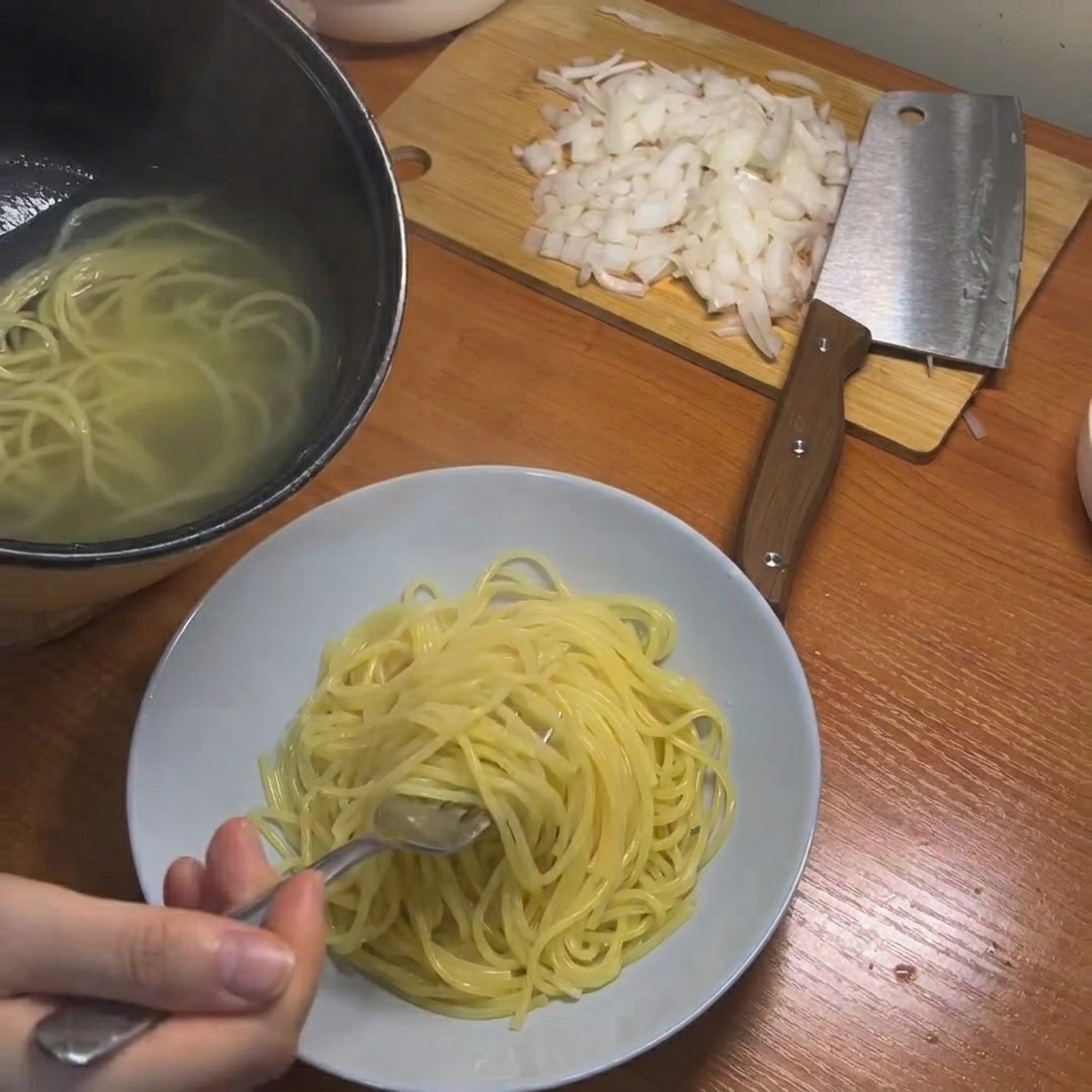 Cooked spaghetti being lifted from the pot using chopsticks.