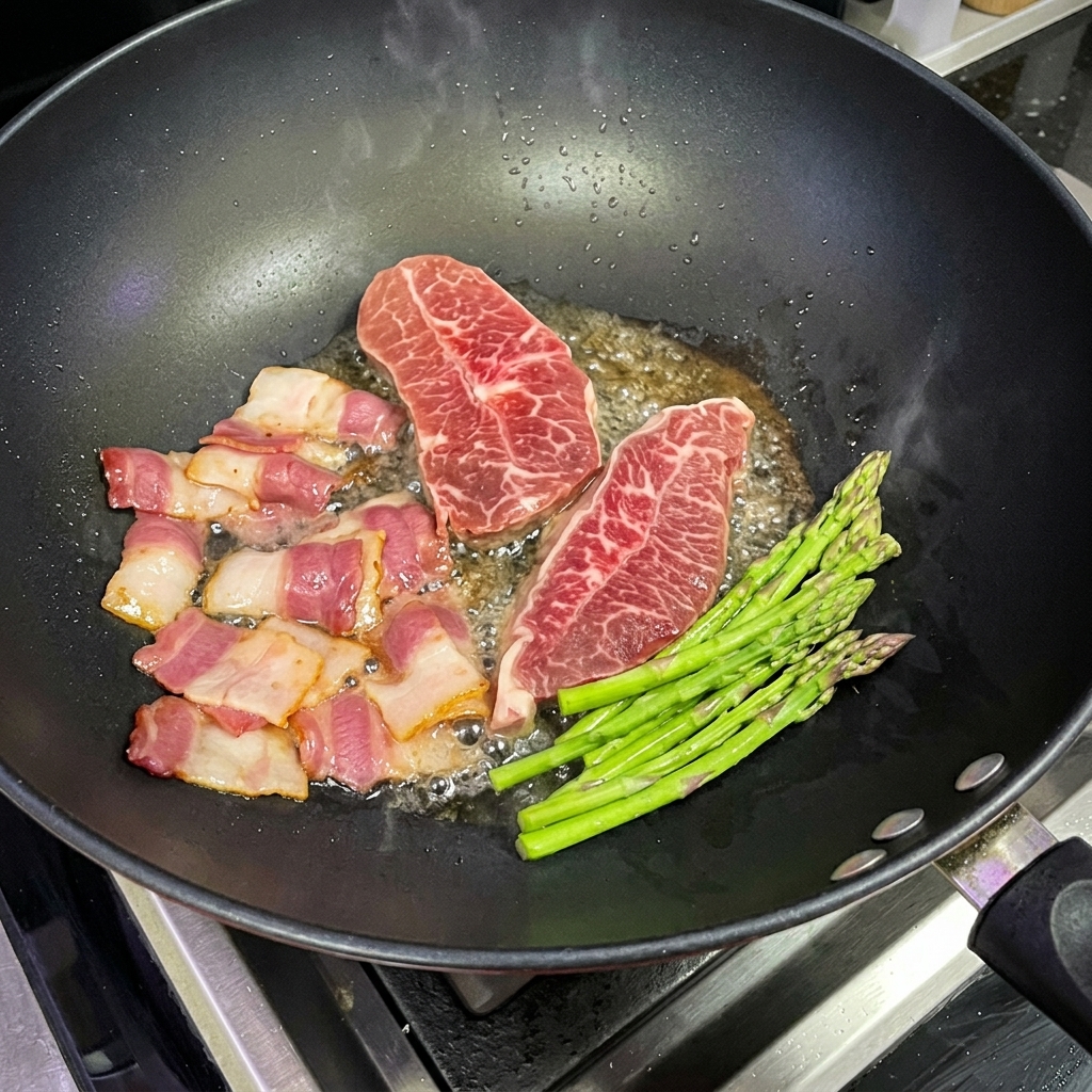 Fresh asparagus spears being pan-fried in a wok alongside steak and bacon.