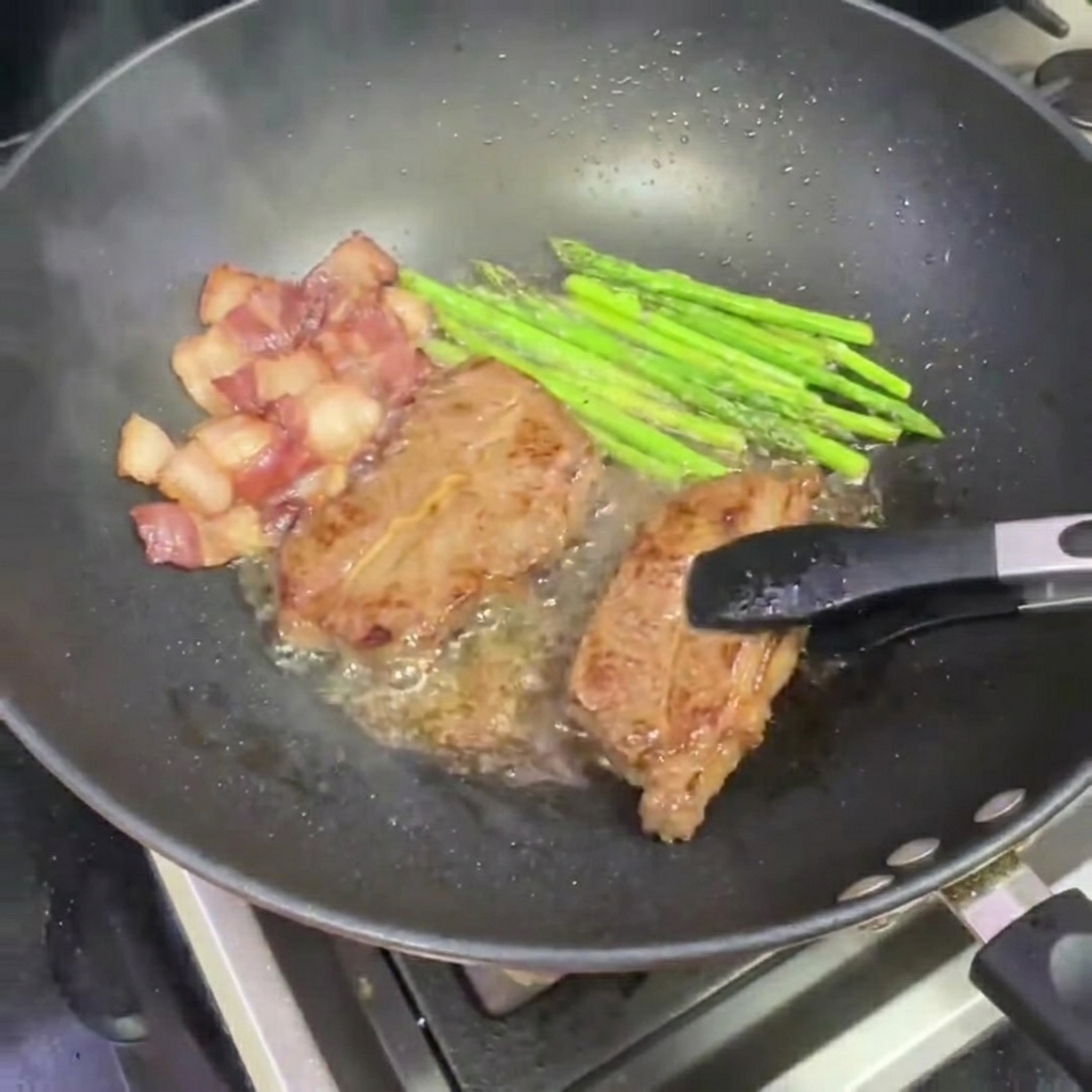 Tongs removing a piece of seared steak from the wok.