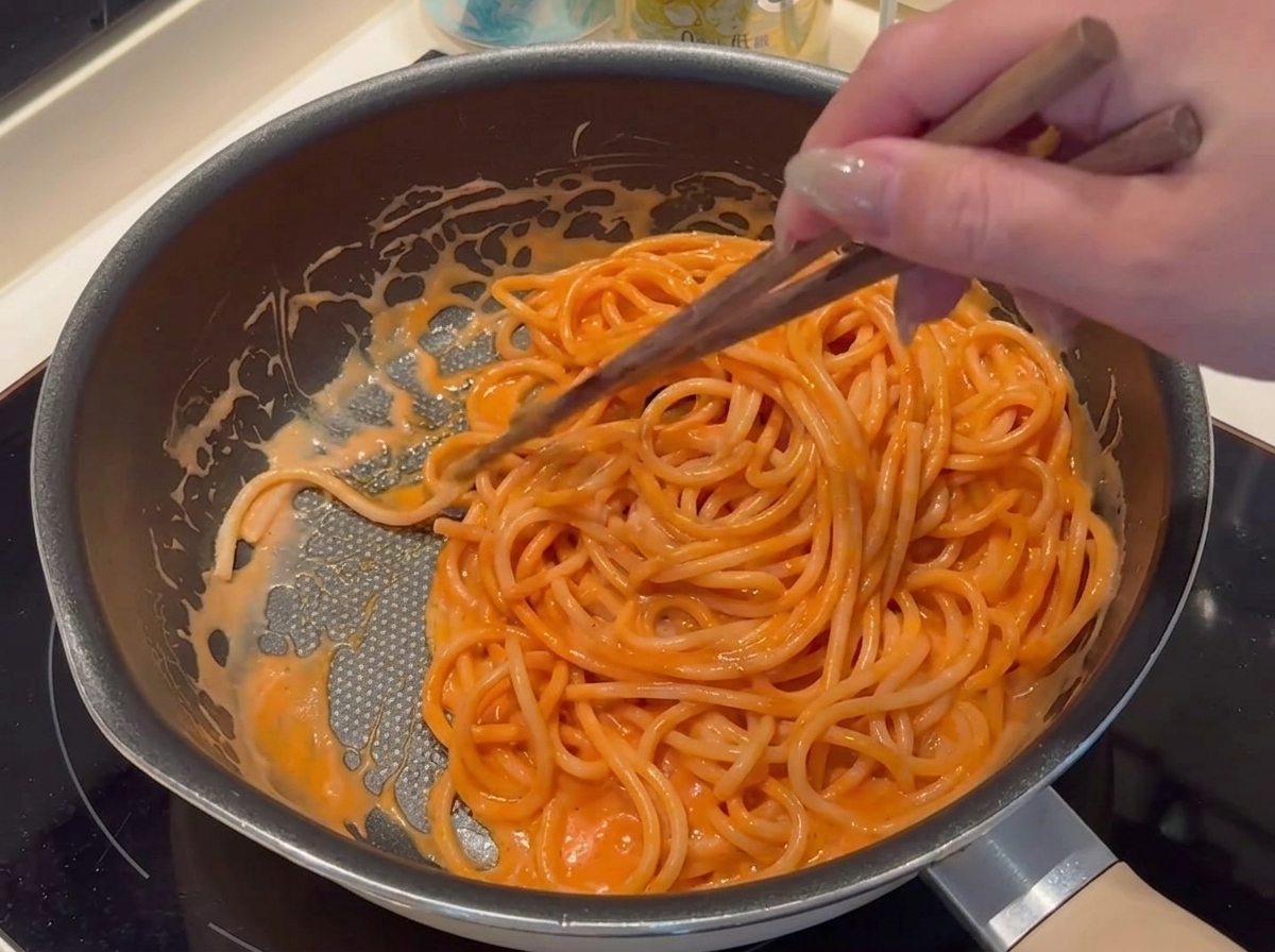 Breadcrumbs being sprinkled carefully around the dough perimeter of the assembled pizza.