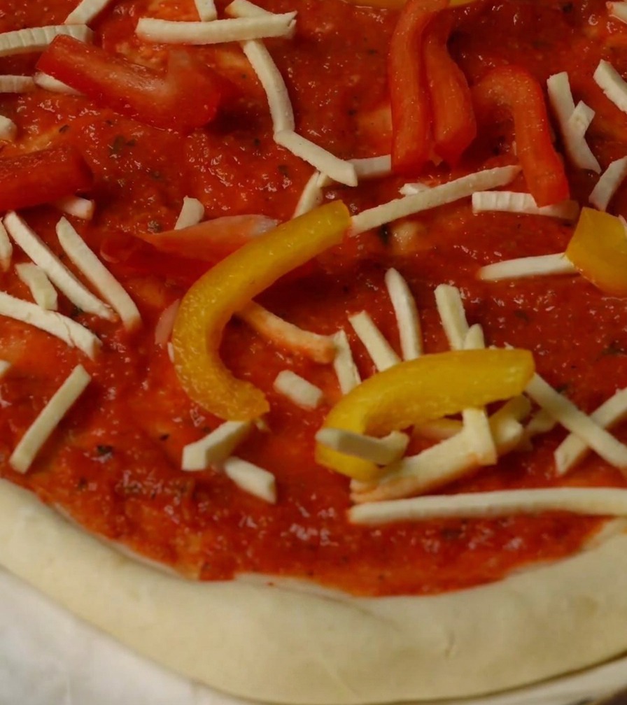 Pizza topped with bell peppers, cheese, and lobster pieces, ready for the oven.