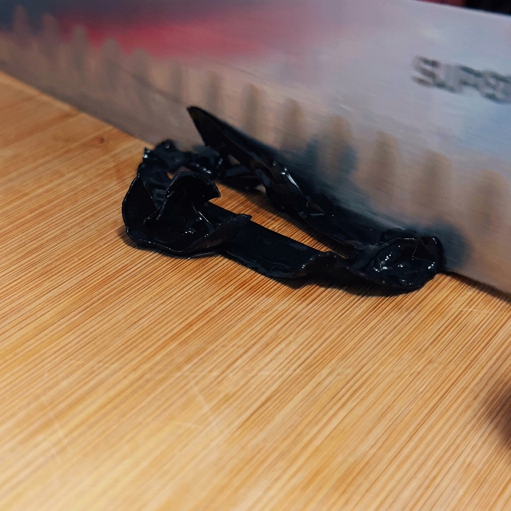 A sharp knife slicing blanched wood ear mushrooms into thin, dark strips on a wooden board.