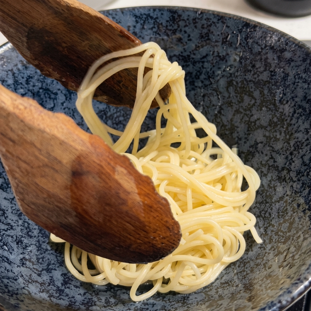 Cooked ramen noodles being lifted from a pot with a large wooden spoon.