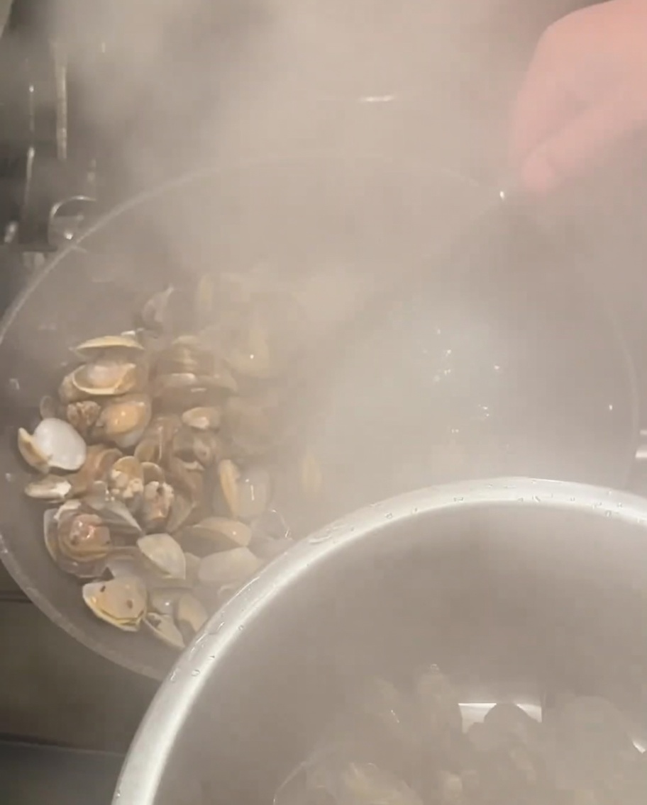 Strainer scooping opened clams from the boiling pot.